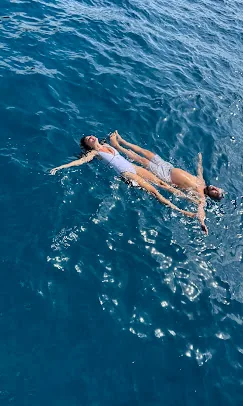 Guest photo: floating at the swim stop Two guests floating on their backs in deep blue water at the swim stop